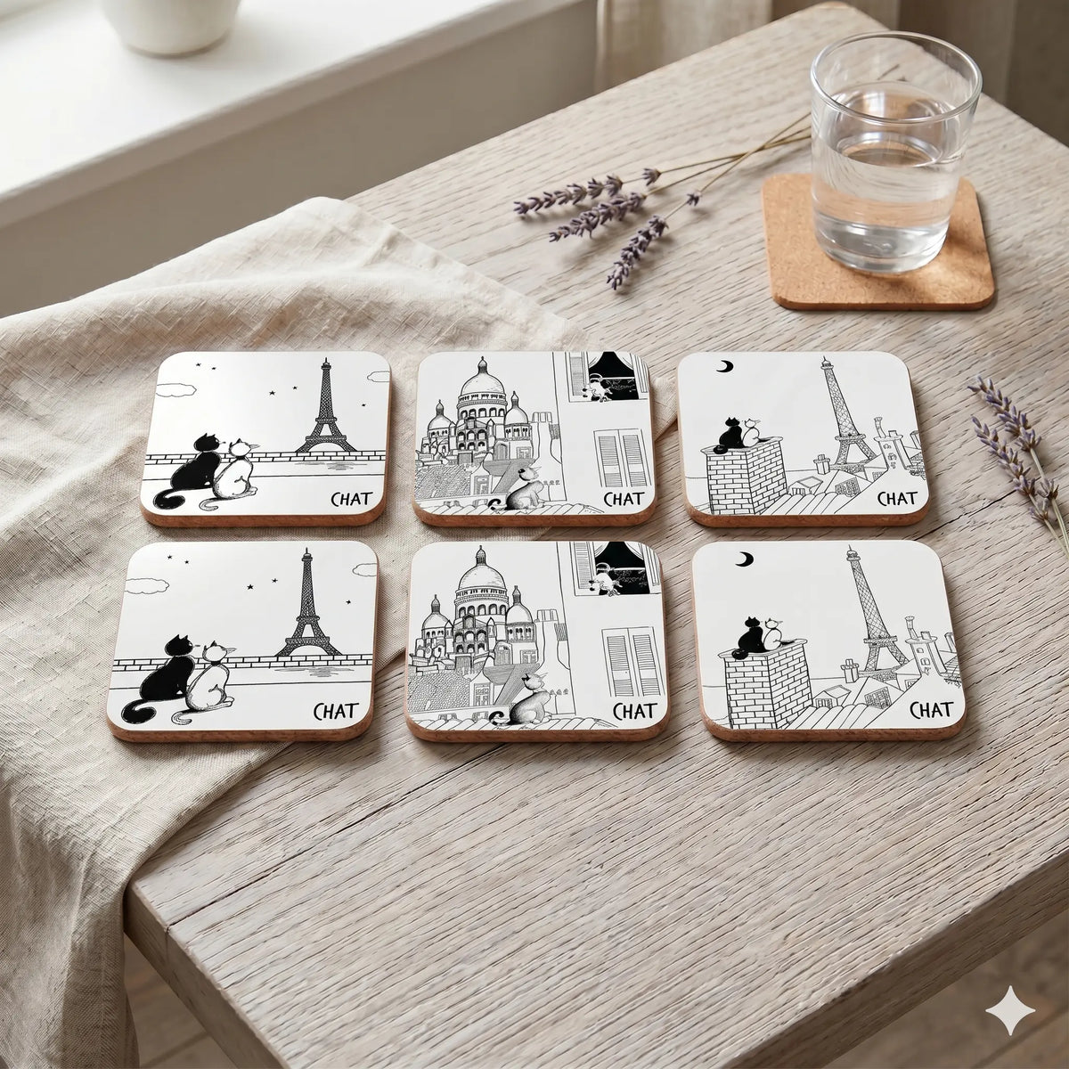 Set of six coasters with black and white designs on a wooden surface with a glass of water and lavender.